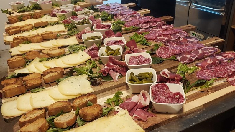 Plateau de charcuterie avec viandes, fromages, pain et garnitures variées.