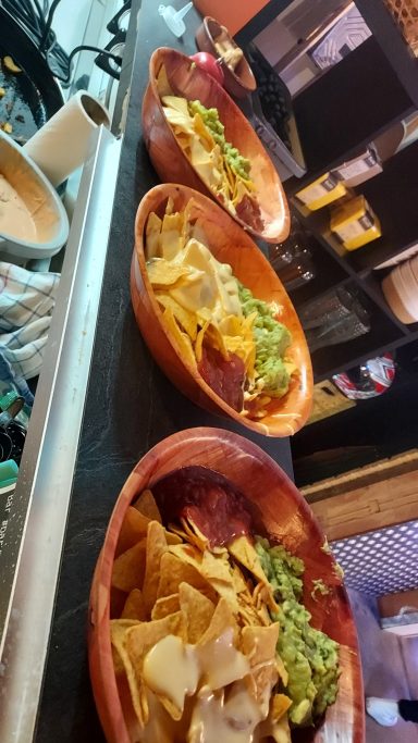 Trois bols de nachos garnis de salsa, guacamole et crème.